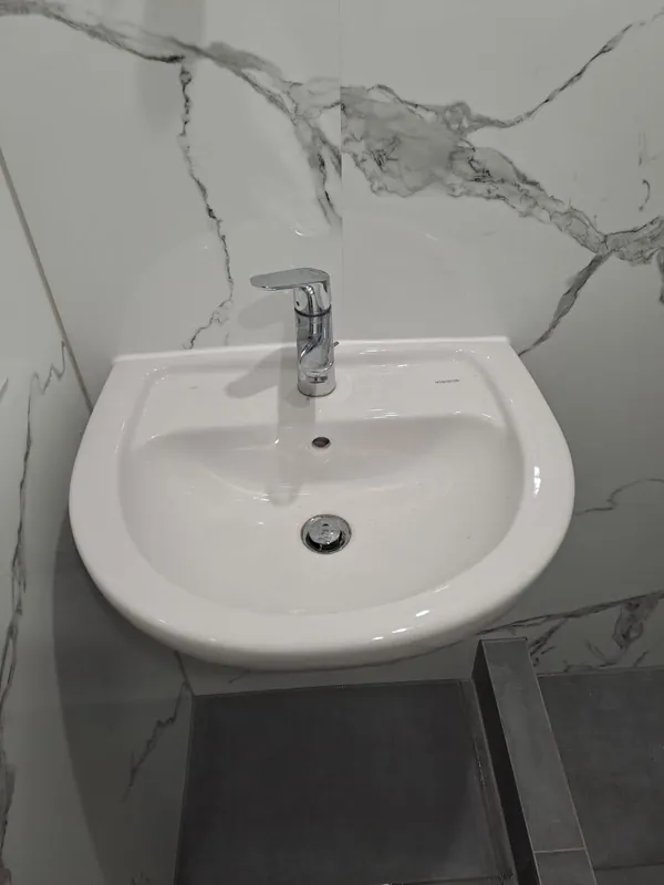 Waschbecken vor Wandfliesen in Marmoroptik