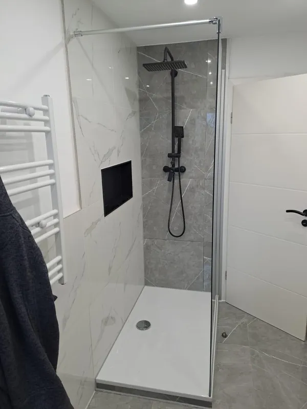 Fertige Walk-in-Dusche mit Wandnische und schwarzen Armaturen